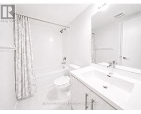 A white bathroom with a toilet, sink, and shower.