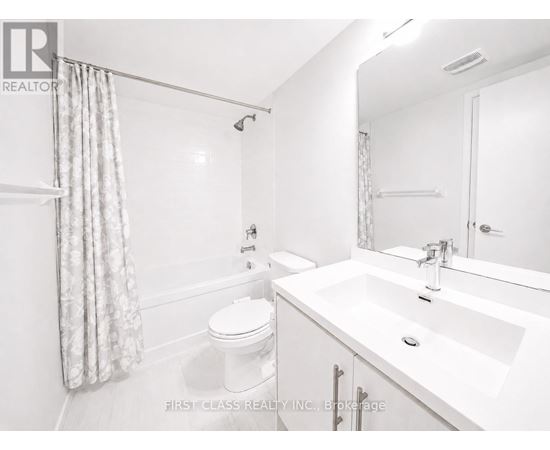 A white bathroom with a toilet, sink, and shower.