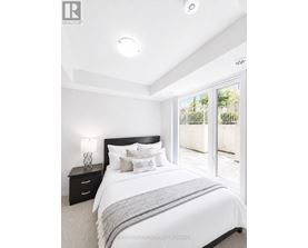 A bedroom with a large bed, nightstand, and sliding glass doors.
