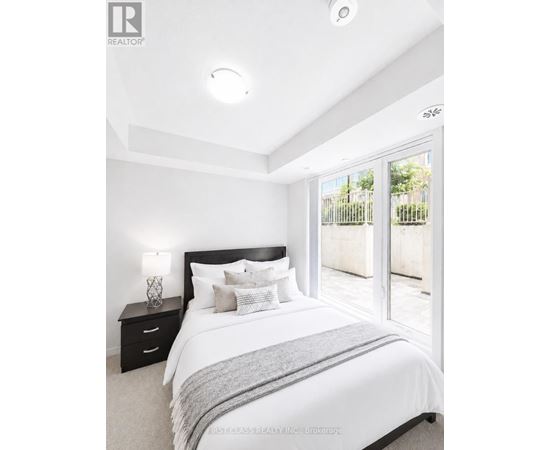 A bedroom with a large bed, nightstand, and sliding glass doors.