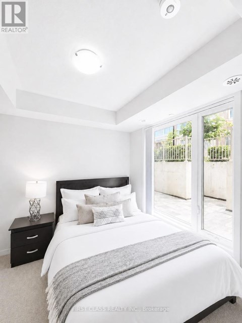 A bedroom with a large bed, nightstand, and sliding glass doors.