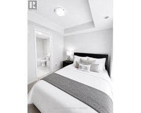 A bedroom with a large bed and a nightstand with a lamp.
