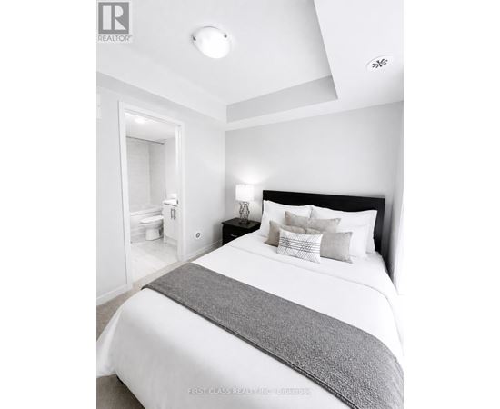 A bedroom with a large bed and a nightstand with a lamp.