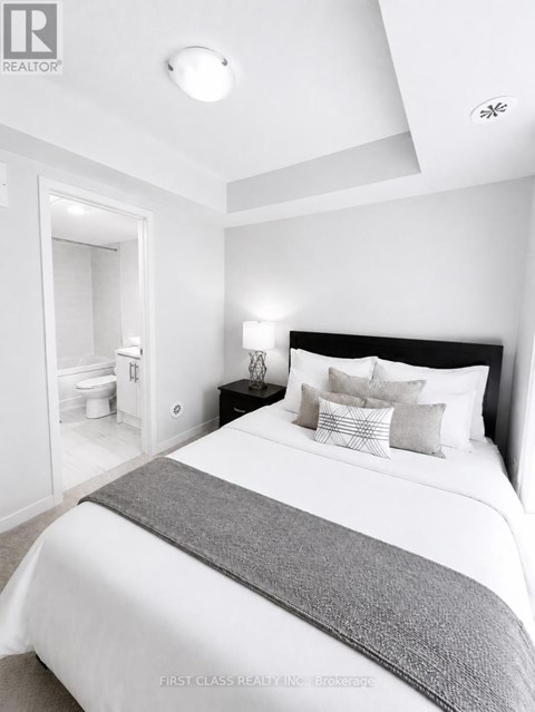 A bedroom with a large bed and a nightstand with a lamp.