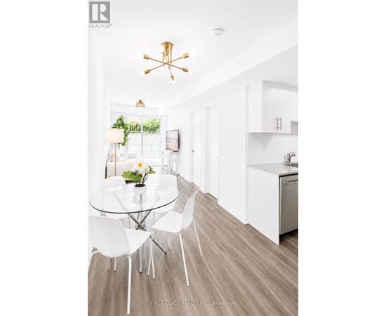 A modern kitchen with a glass table and white chairs.