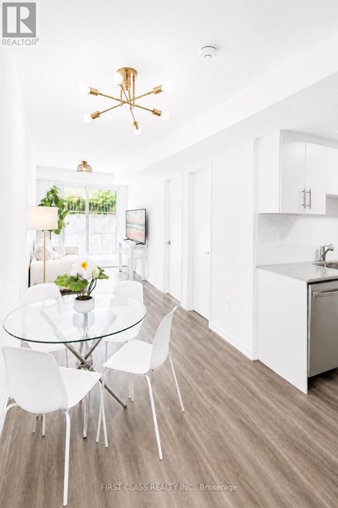 A modern kitchen with a glass table and white chairs.