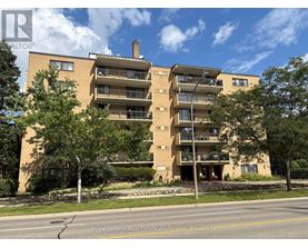 A multi-story apartment building with balconies and a tree in front.