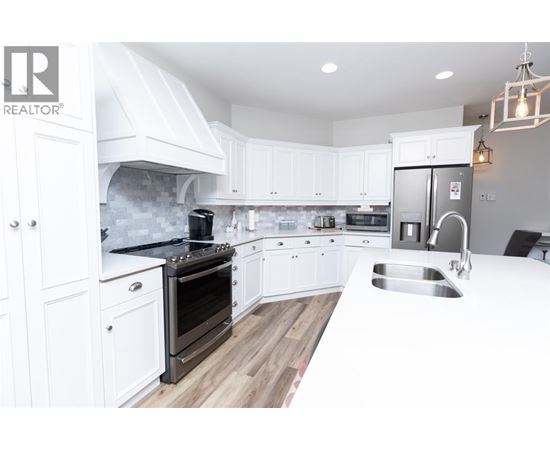 A modern kitchen with white cabinets and a stainless steel refrigerator.