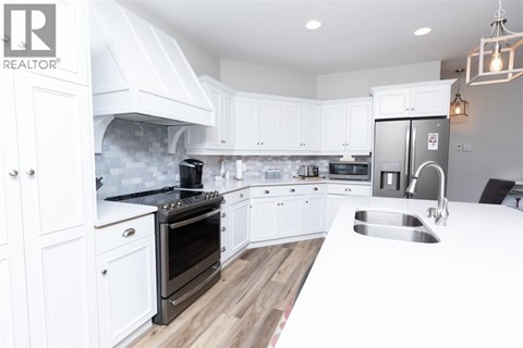 A modern kitchen with white cabinets and a stainless steel refrigerator.