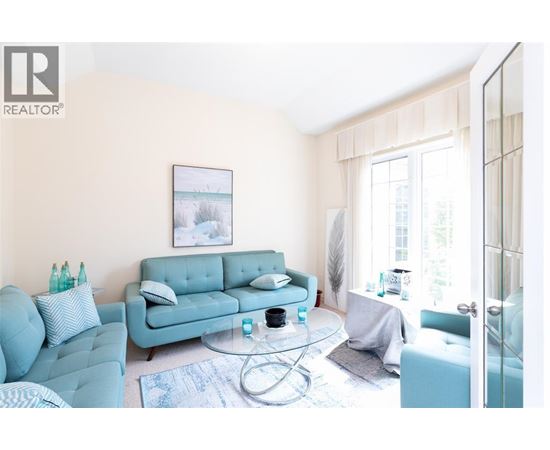A living room with a blue couch and a glass table.