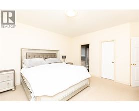 A bedroom with a large bed and a nightstand.