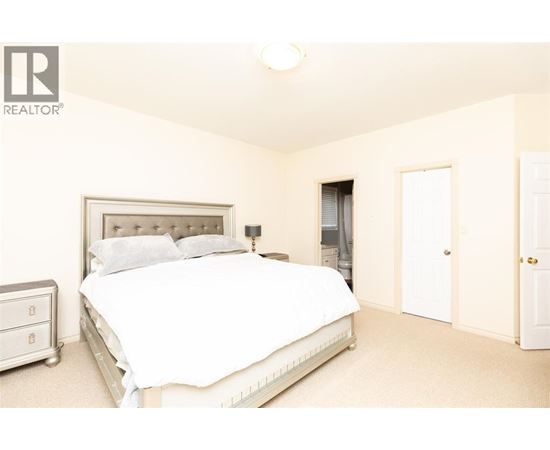 A bedroom with a large bed and a nightstand.