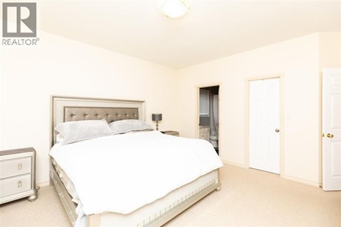 A bedroom with a large bed and a nightstand.