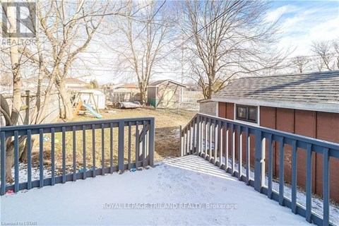 A snow-covered deck with a railing and a small building in the background.