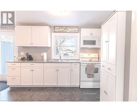 A white kitchen with a sign that says "Sunday Dinner".