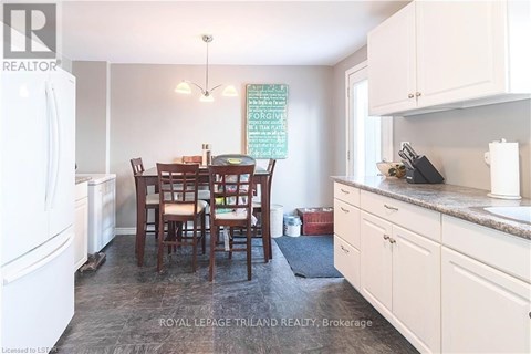 A kitchen with white cabinets and a dining table with chairs.