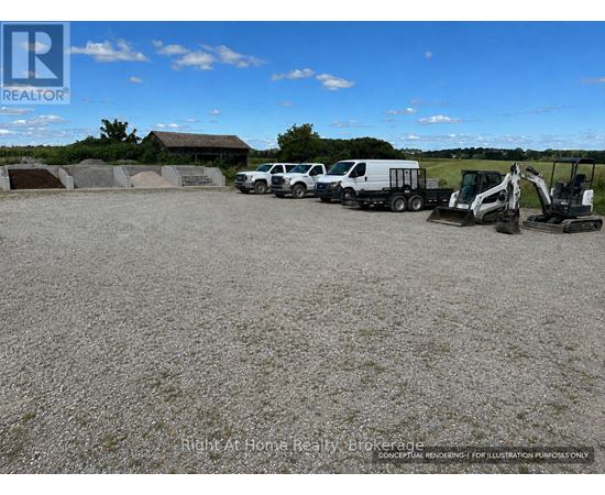 A gravel lot with construction vehicles and a building in the background.