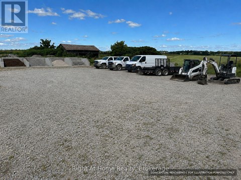 A gravel lot with construction vehicles and a building in the background.