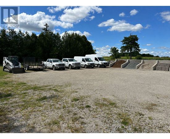 A gravel lot with a row of parked cars and a trailer.