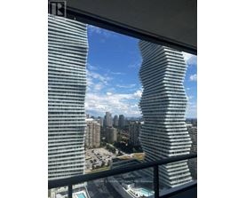A tall, curved building stands next to a series of smaller buildings.