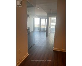 A spacious room with wooden floors and a large window overlooking the city.