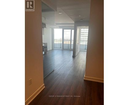 A spacious room with wooden floors and a large window overlooking the city.