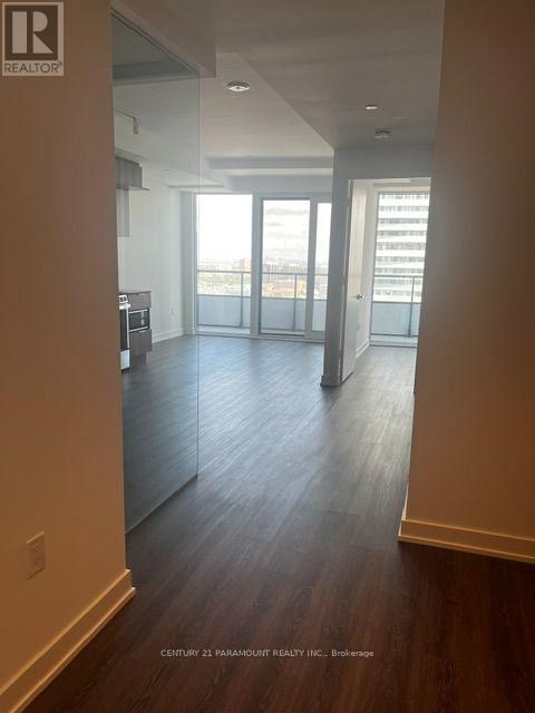 A spacious room with wooden floors and a large window overlooking the city.