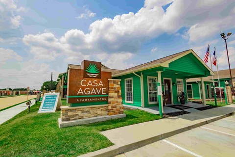 The Casa Agave Apartments building has a green awning and a sign with a green agave symbol on it.