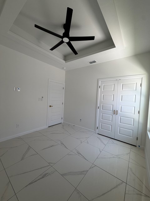 A room with a ceiling fan and two doors.