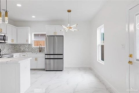 A modern kitchen with a marble floor and a stainless steel refrigerator.