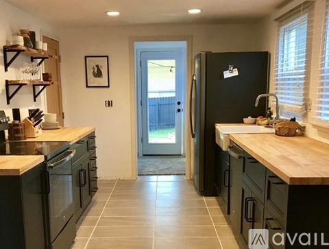 A kitchen with black cabinets and a black fridge.