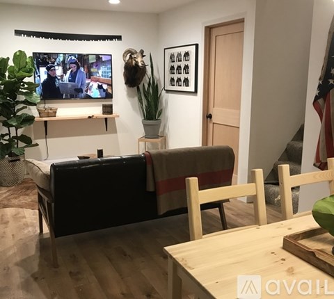 A living room with a couch, a television, and a potted plant.