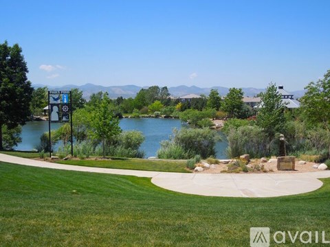 A park with a lake and a signpost.