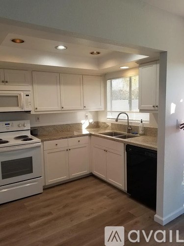 A kitchen with white cabinets and a wooden floor.