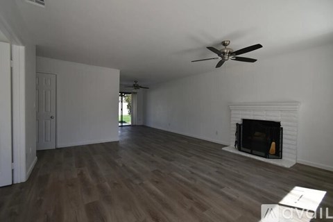A living room with a fireplace and a ceiling fan.