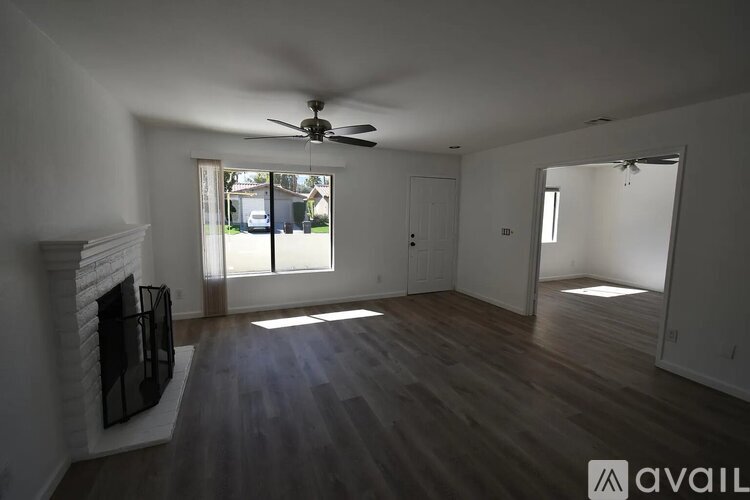 A spacious room with a fireplace and a ceiling fan.