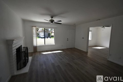 A spacious room with a fireplace and a ceiling fan.