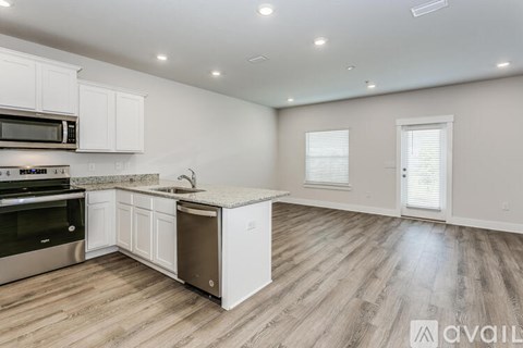 A kitchen with white cabinets and a wooden floor.