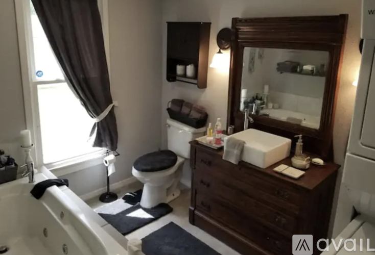 A bathroom with a white tub, a toilet, a sink, and a mirror.