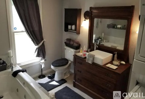 A bathroom with a white tub, a toilet, a sink, and a mirror.