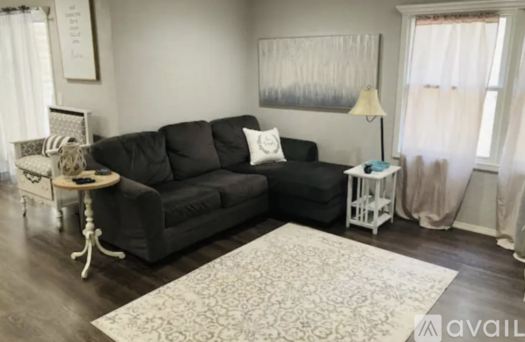 A living room with a black couch and a white side table.