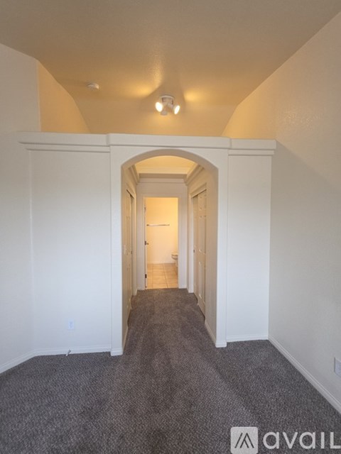 A hallway with a carpeted floor and white walls.