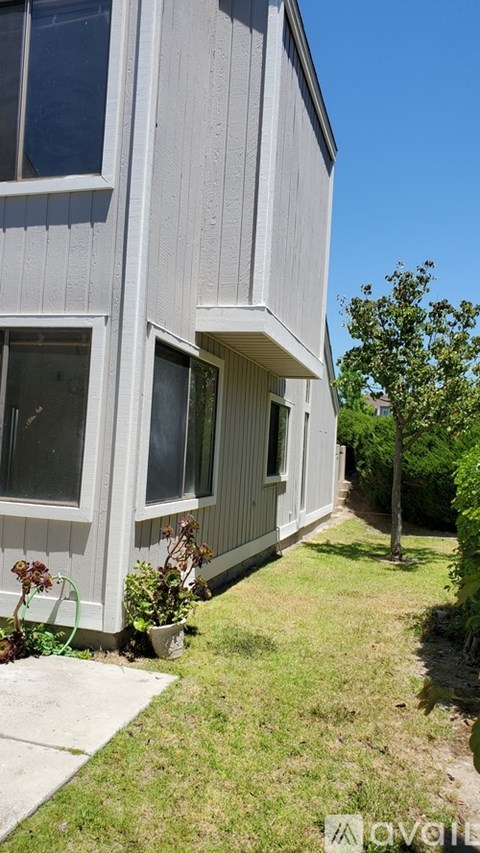 A house with a grey exterior and a small tree in front.