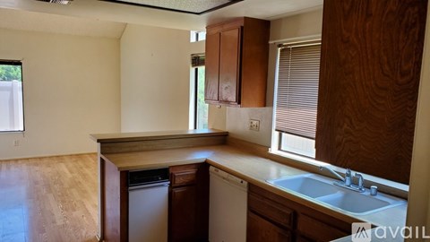A kitchen with wooden cabinets and a window with blinds.