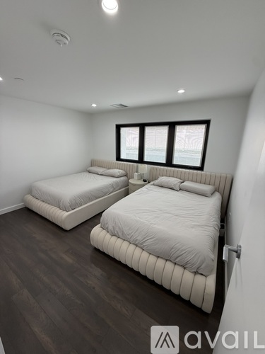 A bedroom with two beds and a window.