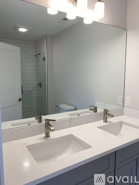 A bathroom with a white counter top and a large mirror.