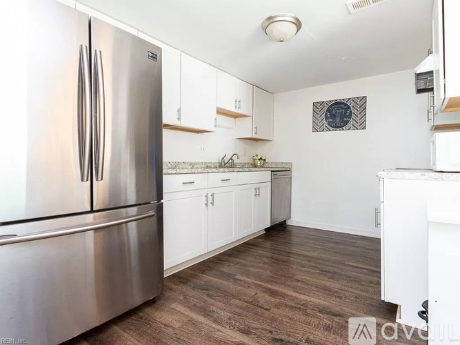 A kitchen with a stainless steel refrigerator and white cabinets.