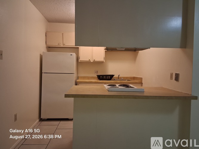 A kitchen with a white refrigerator and a counter with a cutting board on it.
