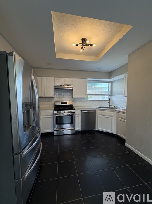 A kitchen with black tile flooring and stainless steel appliances.