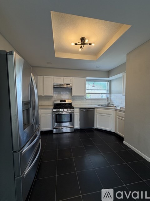 A kitchen with black tile flooring and stainless steel appliances.